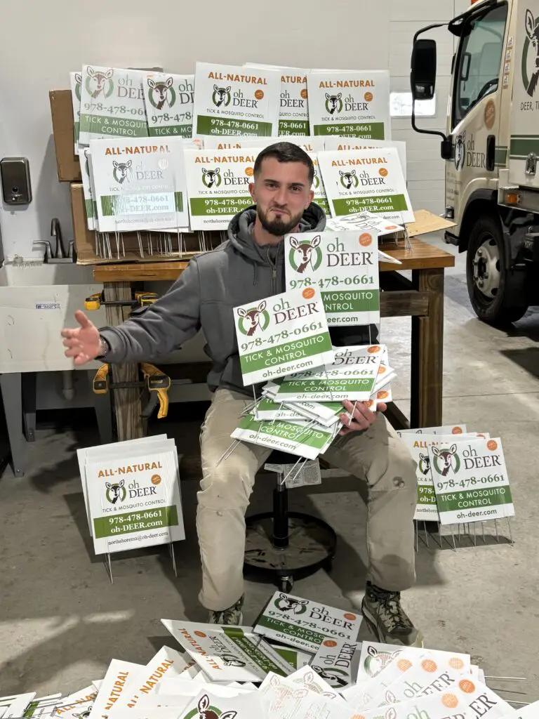 ohDEER technician holding a ton of North Shore yard signs 